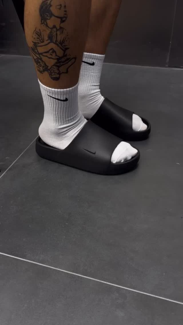 20 Ideal Boyfriend Gifts He'll Actually Use and Keep 18 Black Nike slide sandals and white socks worn on a person's feet.