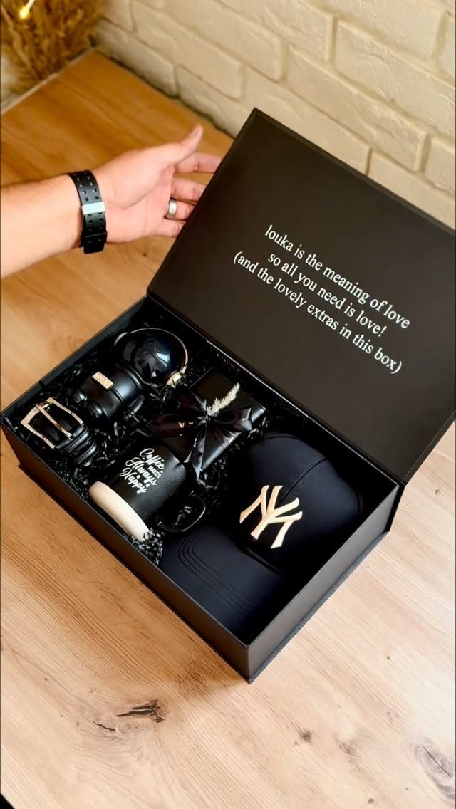 20 Ideal Boyfriend Gifts He'll Actually Use and Keep 19 Black gift box containing a baseball cap, mug, belt, and watch on wood.