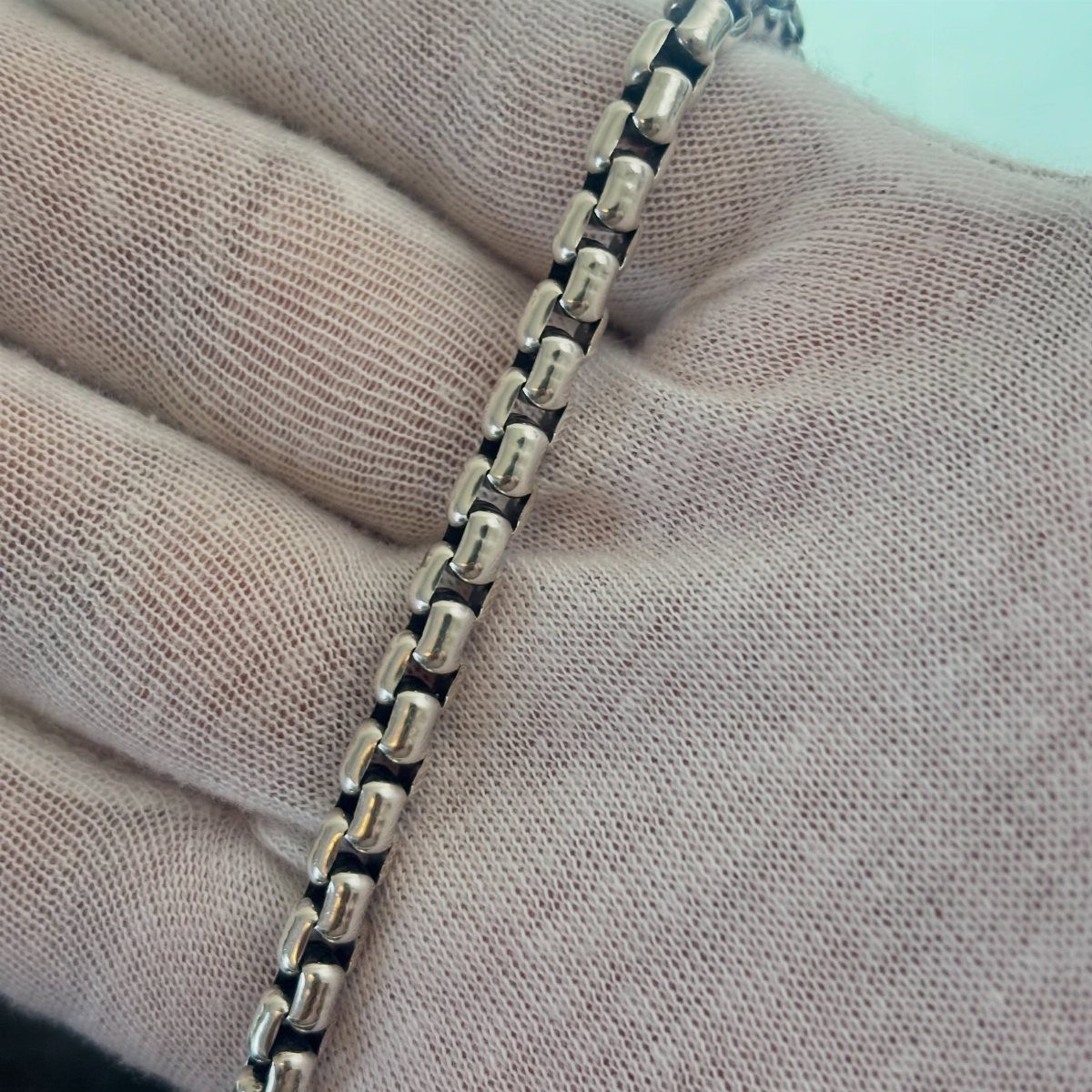 20 Ideal Boyfriend Gifts He'll Actually Use and Keep 15 Silver metal chain bracelet held in a person's open palm.