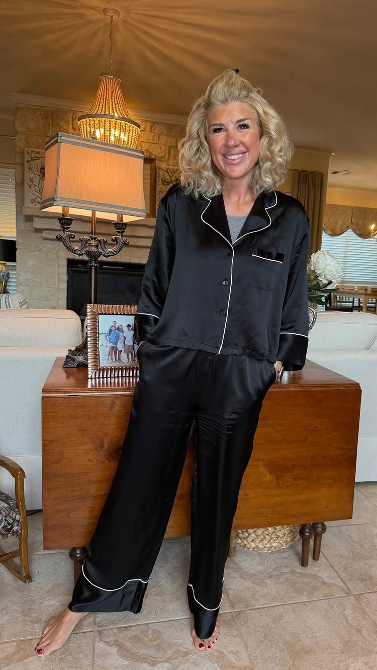 Luxury Gifts for Women: 11 Ideas from Candles to Jewelry 4 Woman wearing a black satin pajama set with white piping in a living room