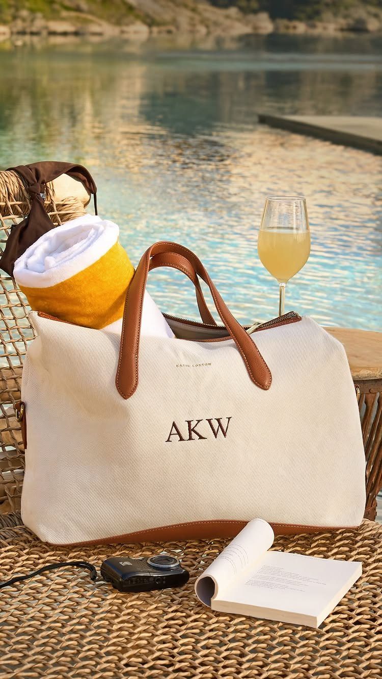 Luxury Gifts for Women: 11 Ideas from Candles to Jewelry 6 White monogrammed travel tote bag with leather handles on a woven outdoor table.