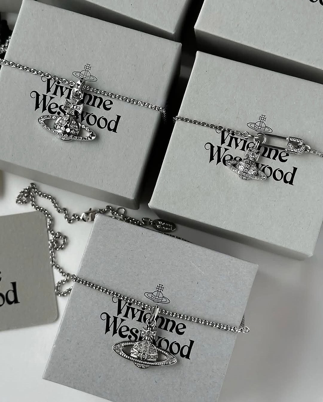 Silver Vivienne Westwood orb bracelets resting on white branded jewelry boxes.