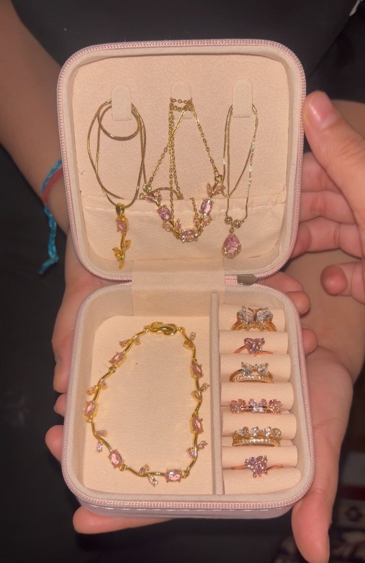 Gold-toned jewelry set with pink gemstones displayed in a small pink travel case.