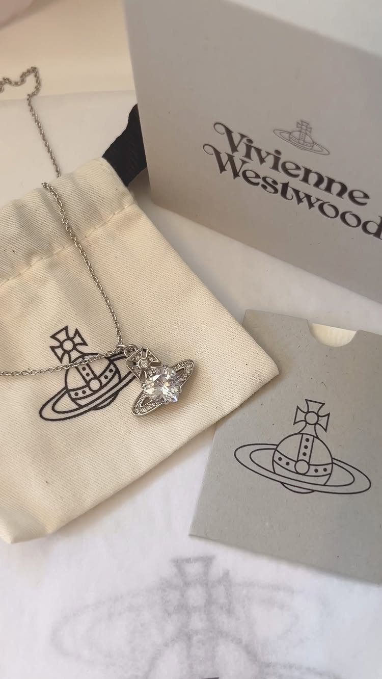 Silver Vivienne Westwood orb necklace with crystal pendant and branded packaging on white surface