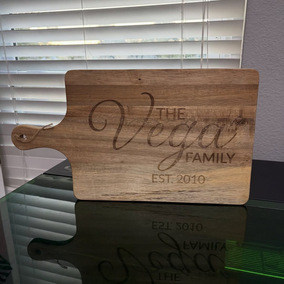 Wooden cutting board engraved with The Vega Family Est. 2010 on reflective surface