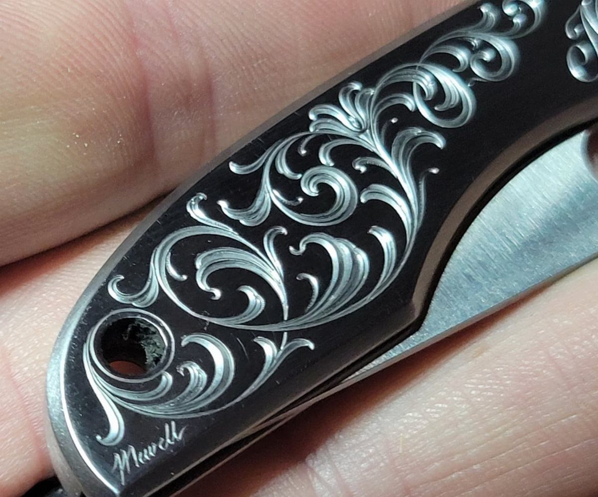 Engraved black pocket knife with silver floral patterns and a personalized name.