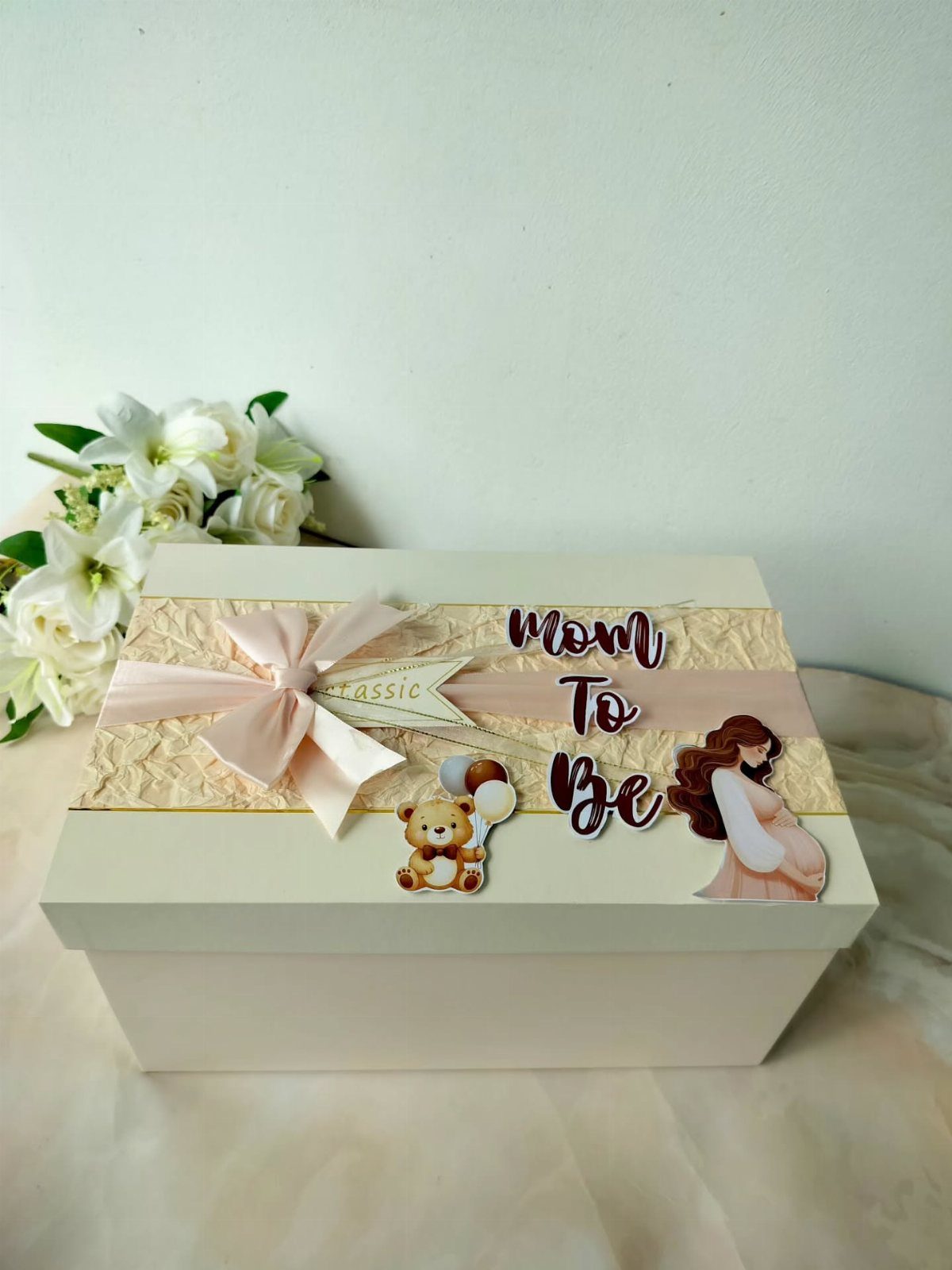 White gift box for a mother to be with pink bow and decorations.