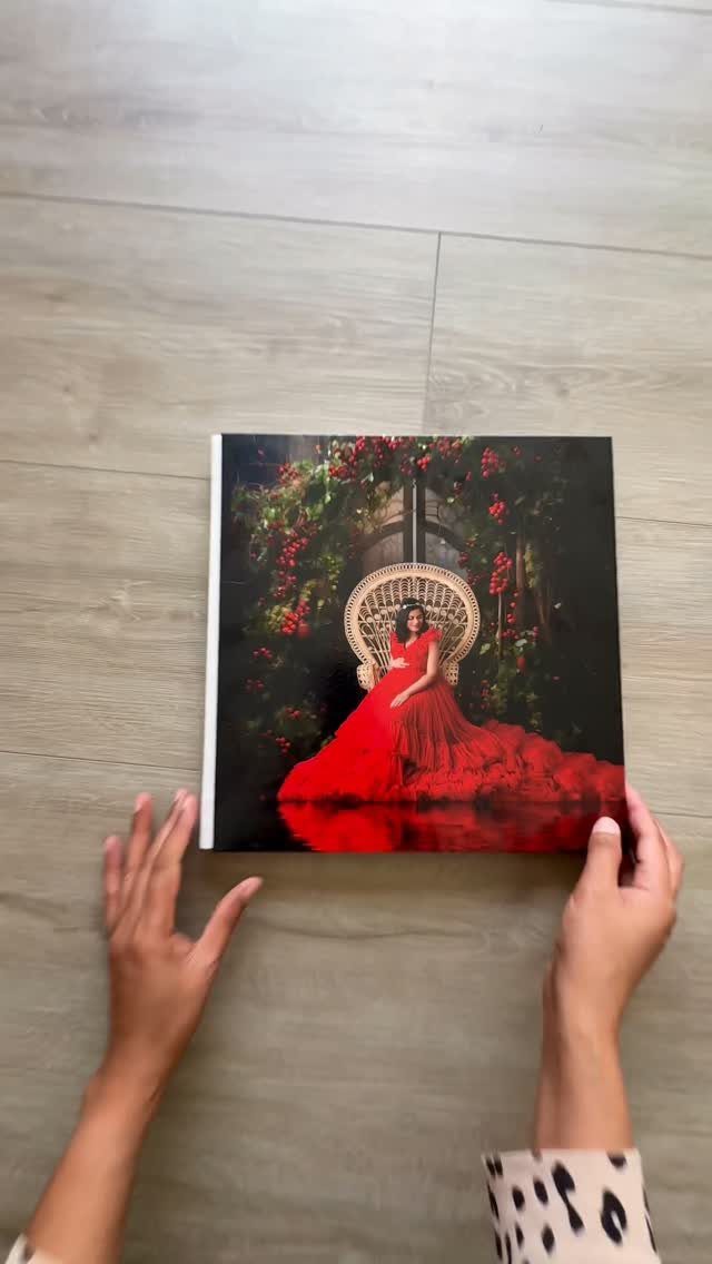 Hands holding a photo album featuring a pregnant woman in a red gown.