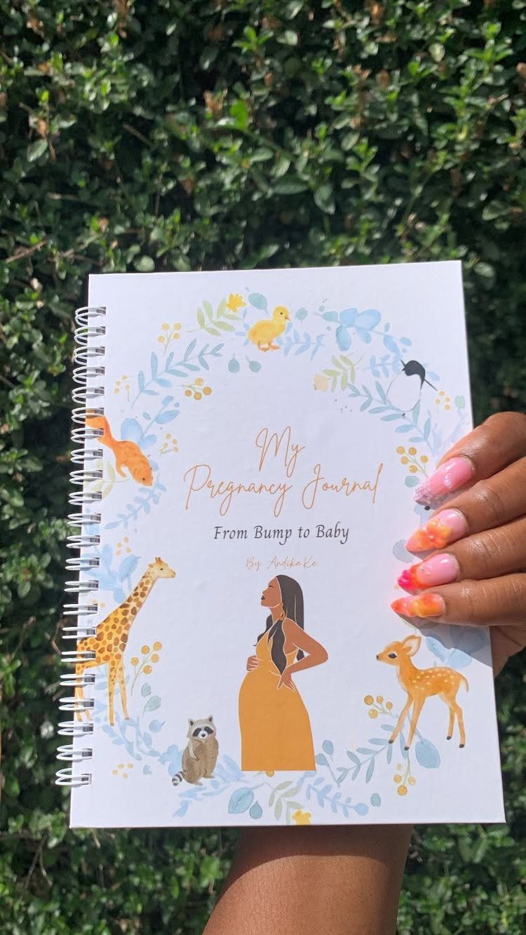 Spiral-bound pregnancy journal with animal illustrations held against a green leafy background.