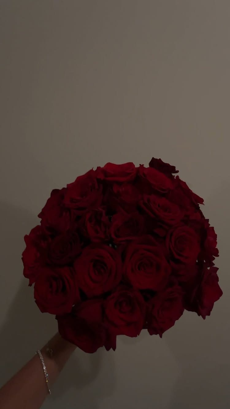 National Boyfriend Day Gifts: 12 Ideas for Him 1 Large bouquet of deep red roses held by a hand against a plain wall
