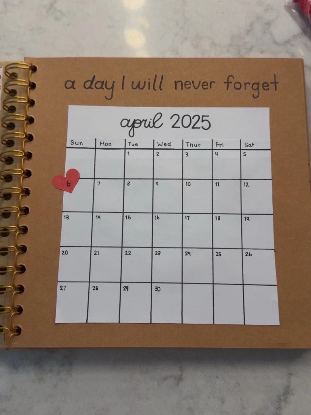 National Boyfriend Day Gifts: 12 Ideas for Him 8 Brown spiral notebook featuring a calendar page with a red heart sticker.