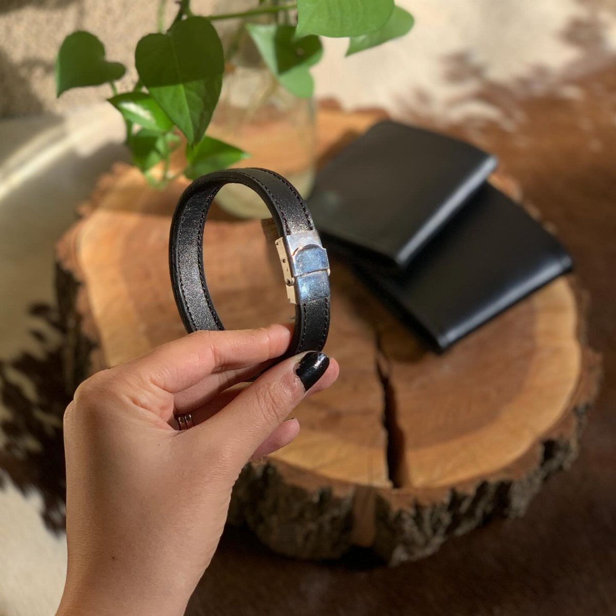 National Boyfriend Day Gifts: 12 Ideas for Him 7 Black leather bracelet and wallets on a wooden slice with a green plant