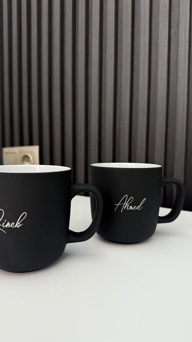 National Boyfriend Day Gifts: 12 Ideas for Him 6 Two matte black personalized mugs with white cursive names on a white surface.