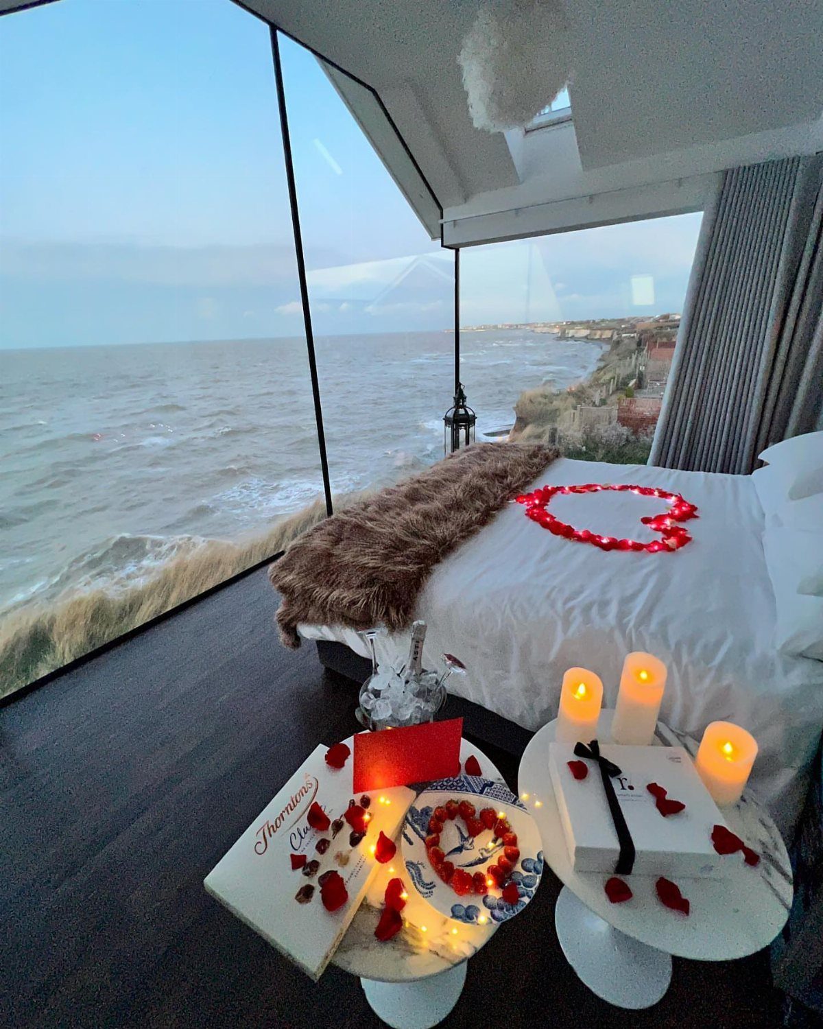 National Boyfriend Day Gifts: 12 Ideas for Him 5 Romantic bedroom setup with rose petals on a bed overlooking the ocean coast