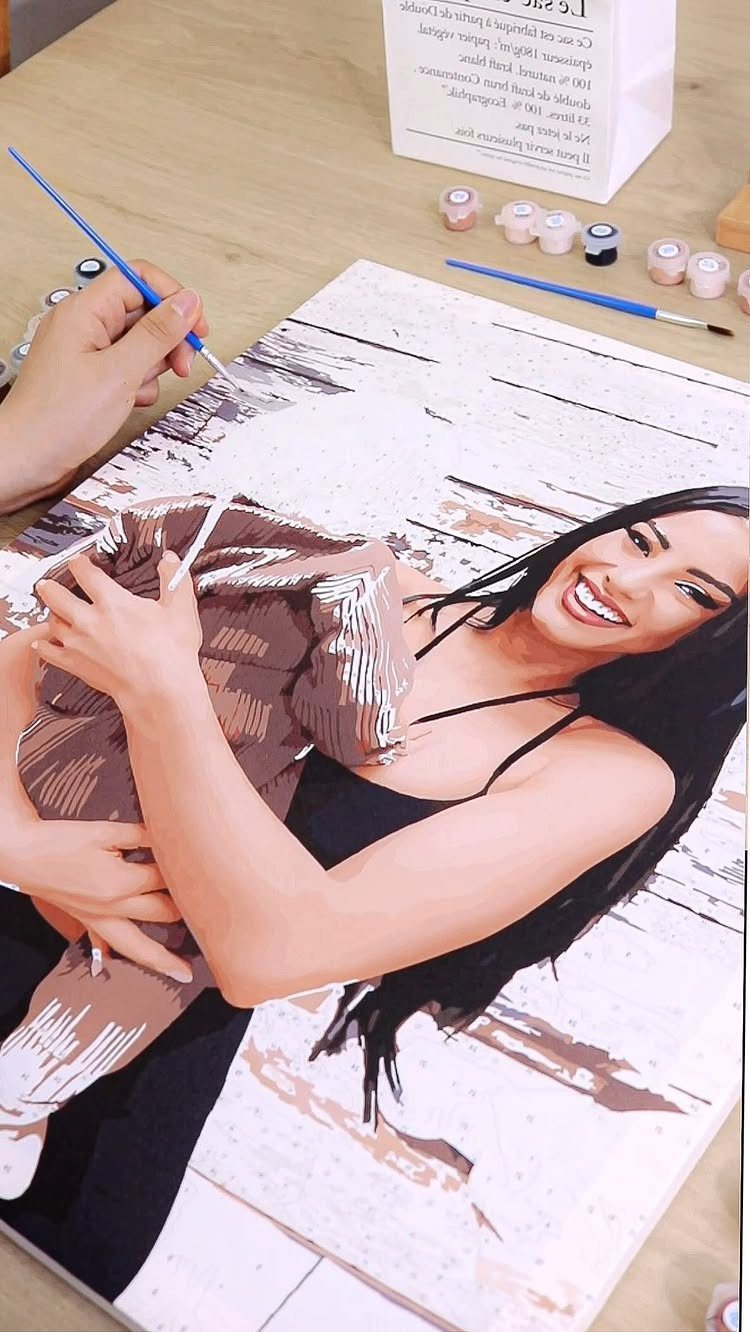 12 Paintings as Gifts for Every Budget and Taste 5 Hand painting a custom paint-by-number canvas of a woman and baby on a table.