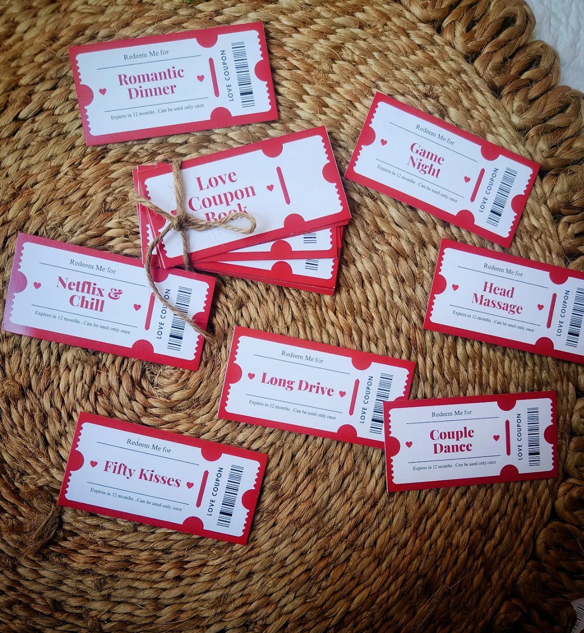 Love coupon book and individual red paper coupons on a woven straw mat.