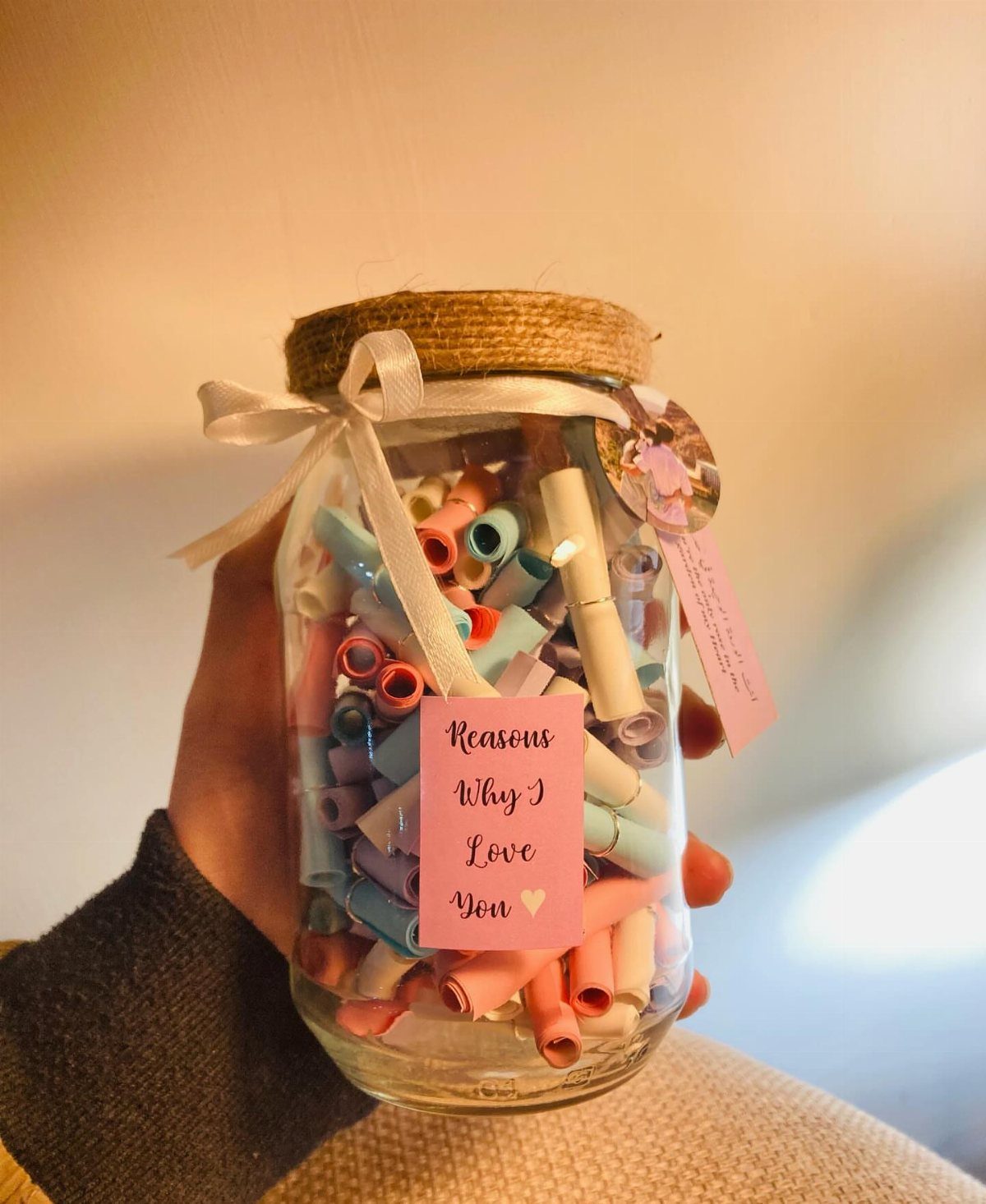 Glass jar filled with rolled colorful paper notes and a love label.