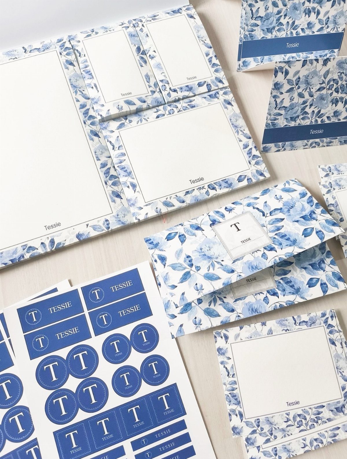 Personalized stationery set with blue floral patterns, including paper, envelopes, and labels.