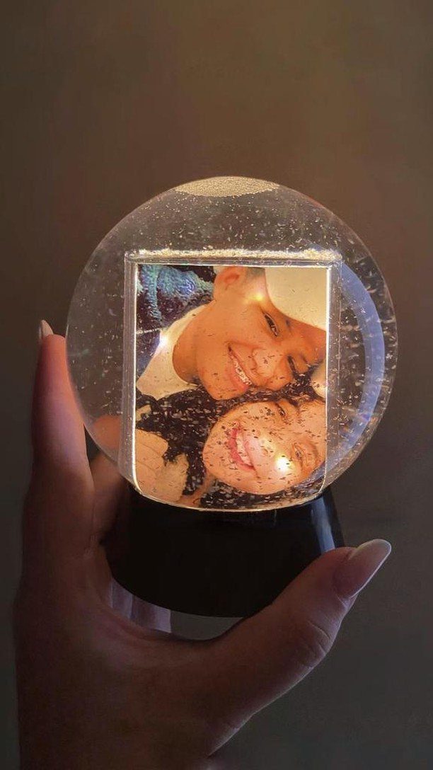 Custom snow globe with a personal photo of two people inside a glittery sphere.