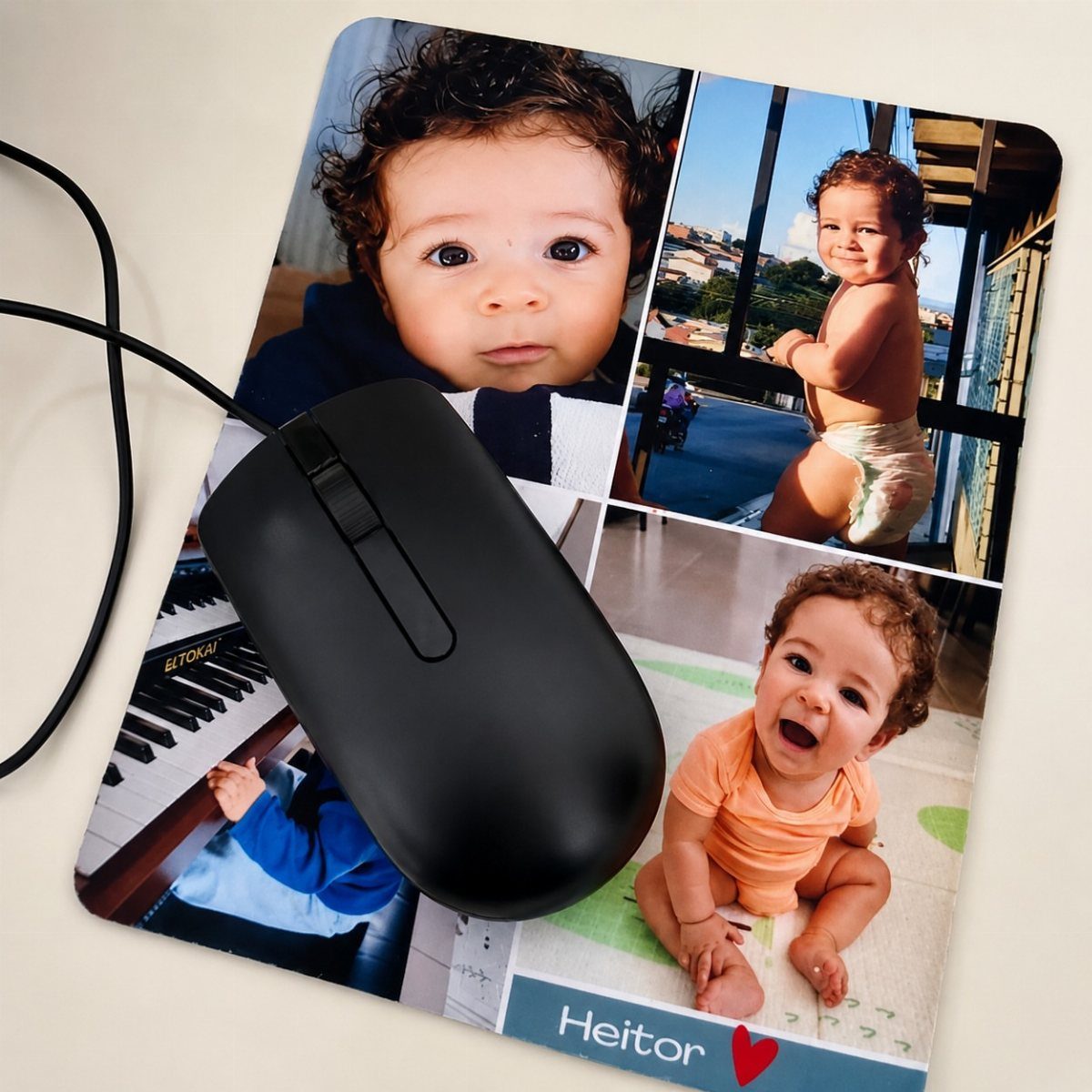 Black computer mouse on a personalized mouse mat featuring photos of a baby boy.