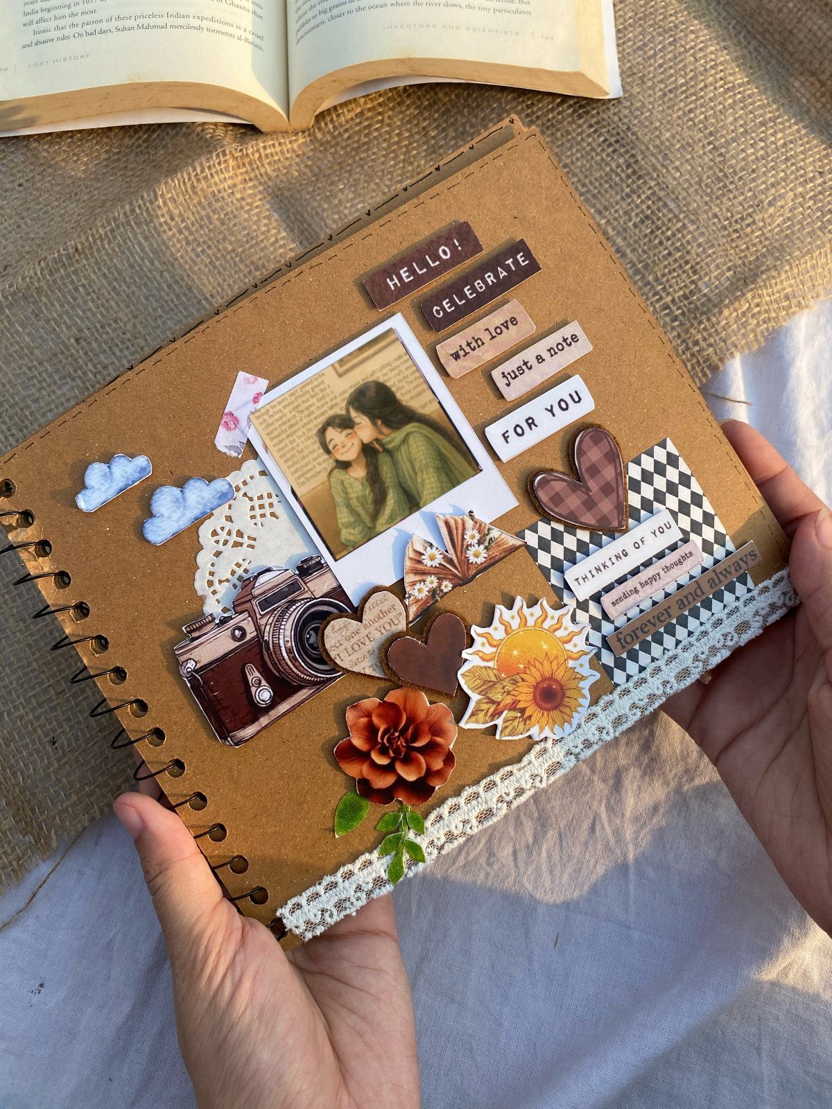 Spiral-bound scrapbook cover decorated with a couple's photo, vintage camera, and floral stickers.
