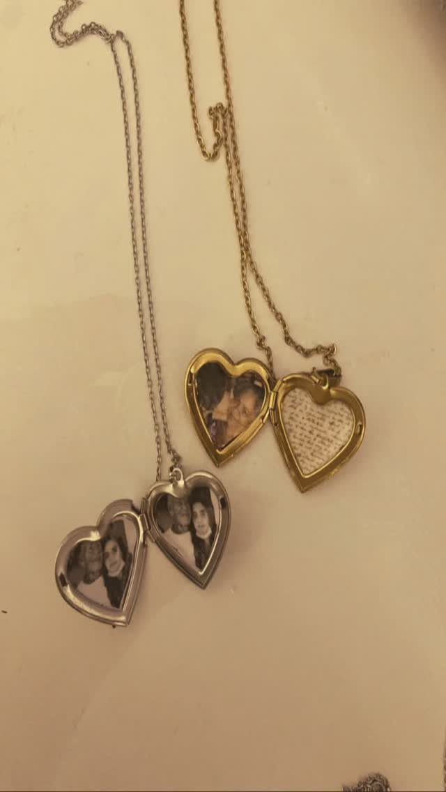 Two heart-shaped photo lockets, one gold and one silver, open to reveal portraits.