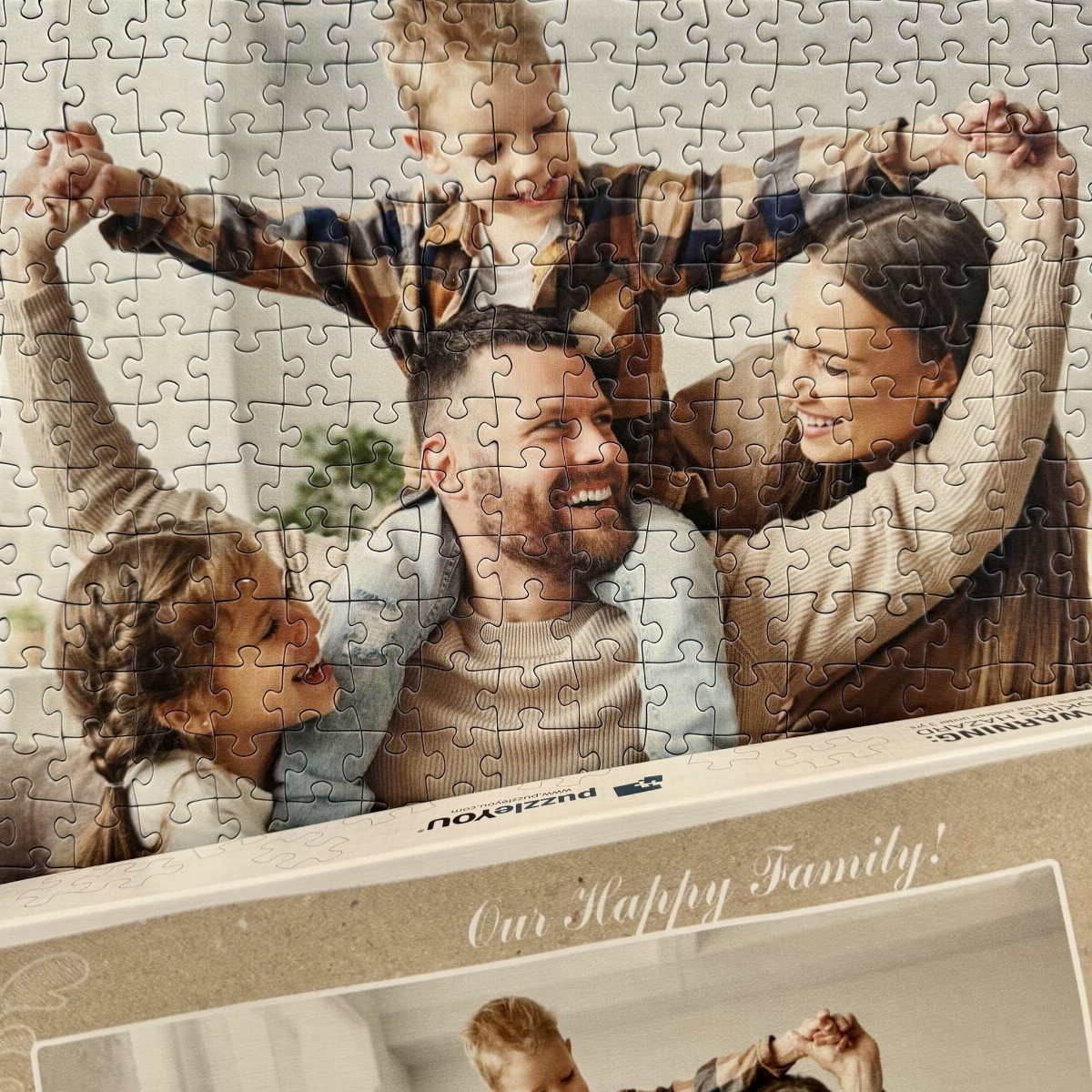 Completed jigsaw puzzle of a happy family resting in its original cardboard box.