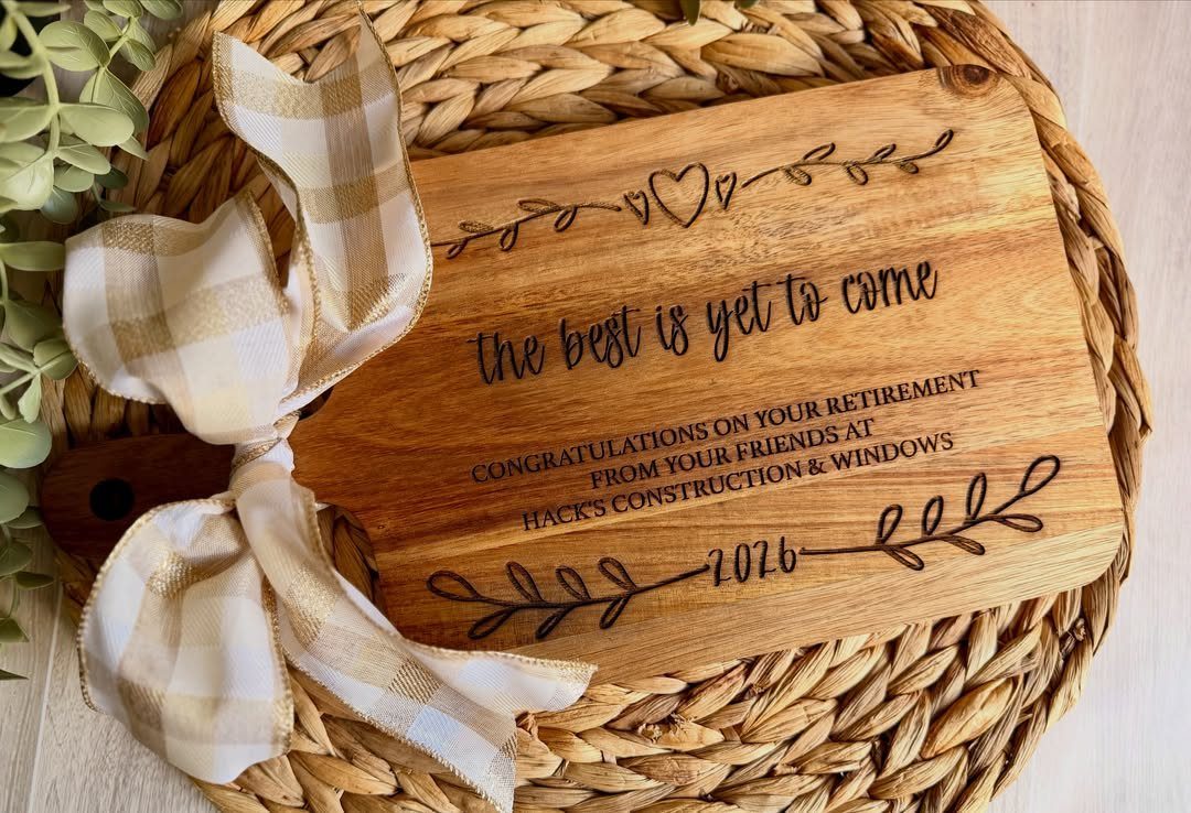 Engraved wooden cutting board with retirement message tied with a checkered ribbon.