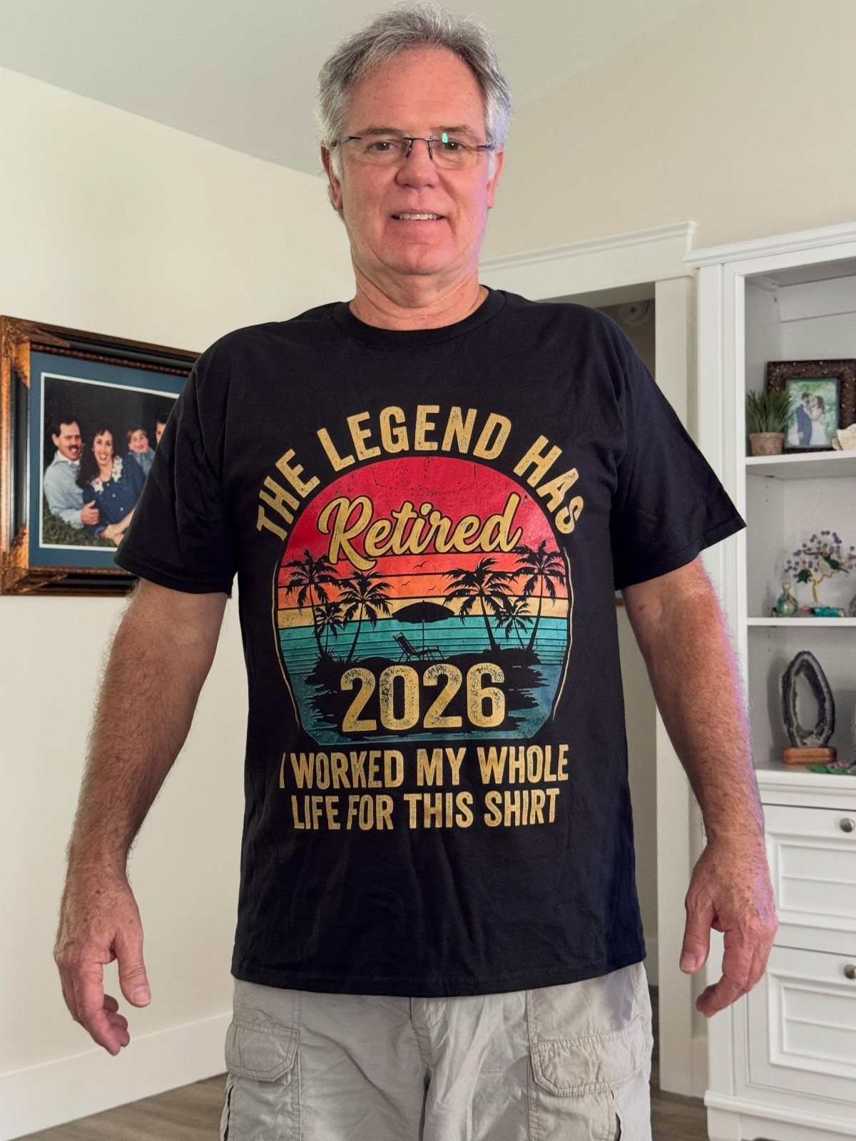 Man wearing a black retirement t-shirt with a tropical sunset design and text.