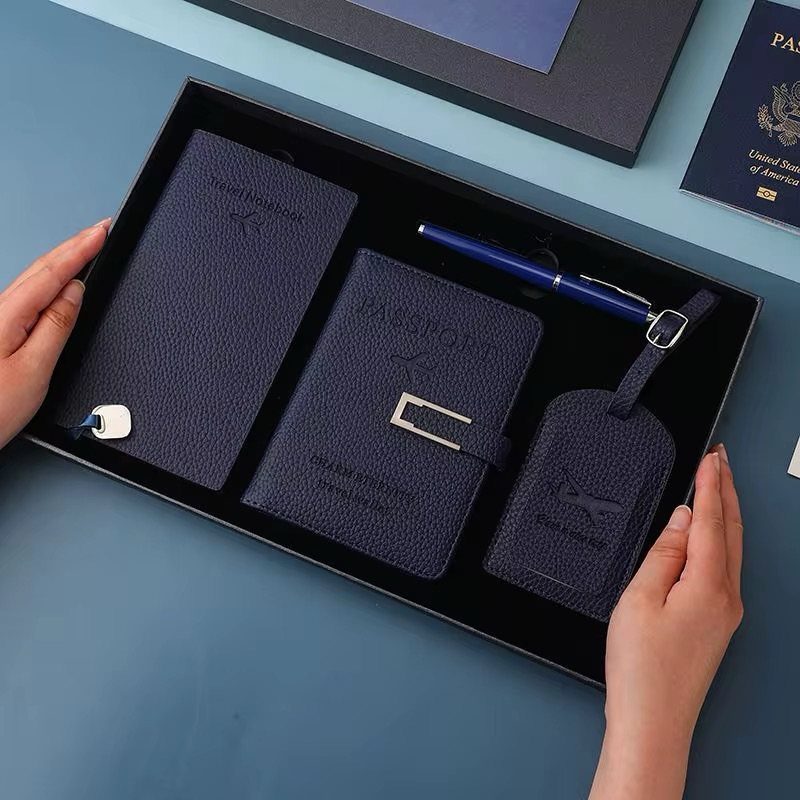 Navy blue leather travel set with notebook, passport holder, and luggage tag in box.