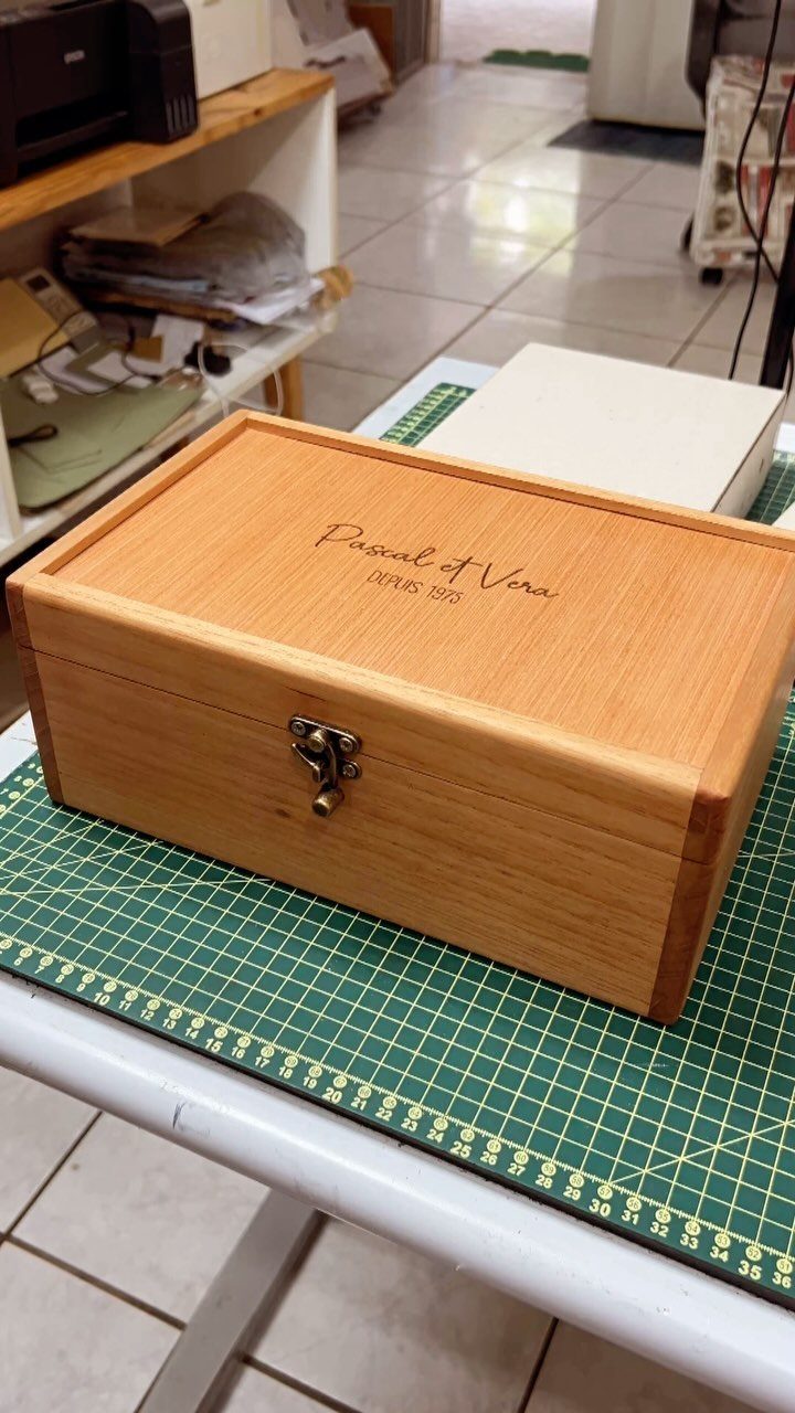 Engraved wooden keepsake box with a metal latch on a green cutting mat.