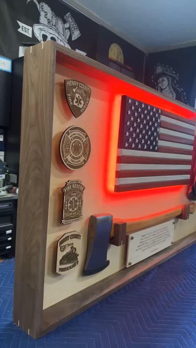 Wooden firefighter retirement shadow box with American flag, badges, and red LED lighting.