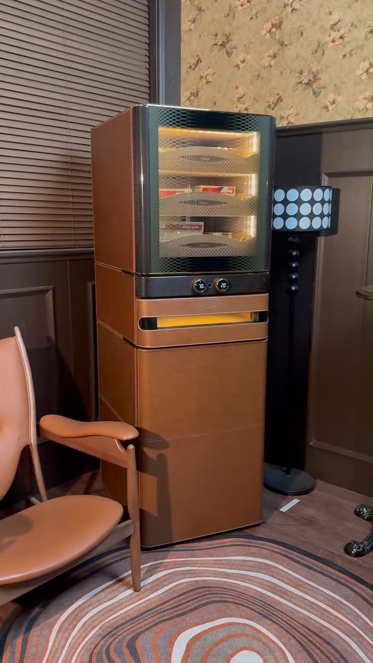 Retro brown mini refrigerator standing next to a leather chair on a patterned rug