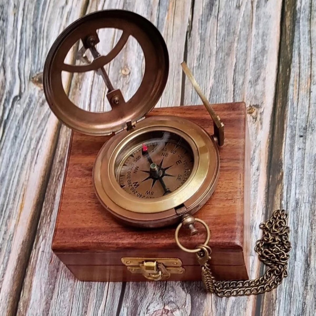 Brass pocket compass resting on a wooden box over a weathered wood background