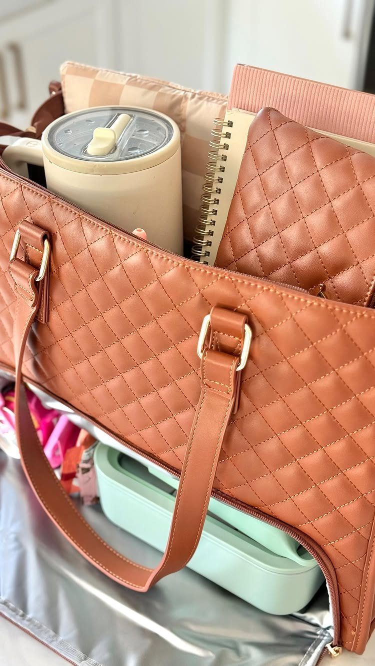 Brown quilted lunch tote containing a travel mug and mint green food container.