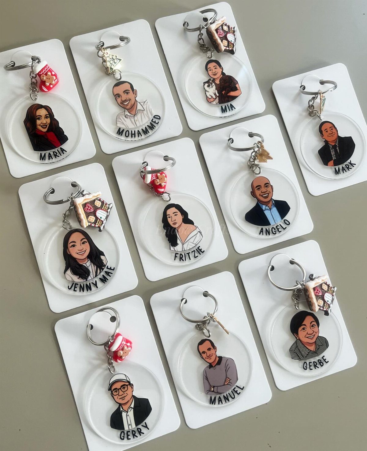 Custom acrylic keychains with cartoon portraits and names on white display cards.