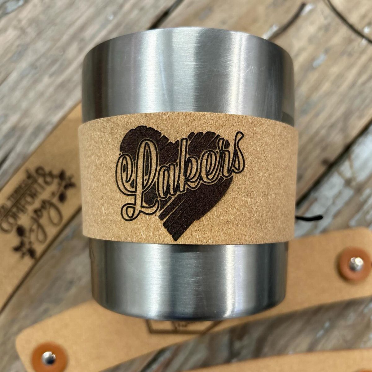 Stainless steel coffee cup with a cork sleeve featuring a Lakers heart logo.