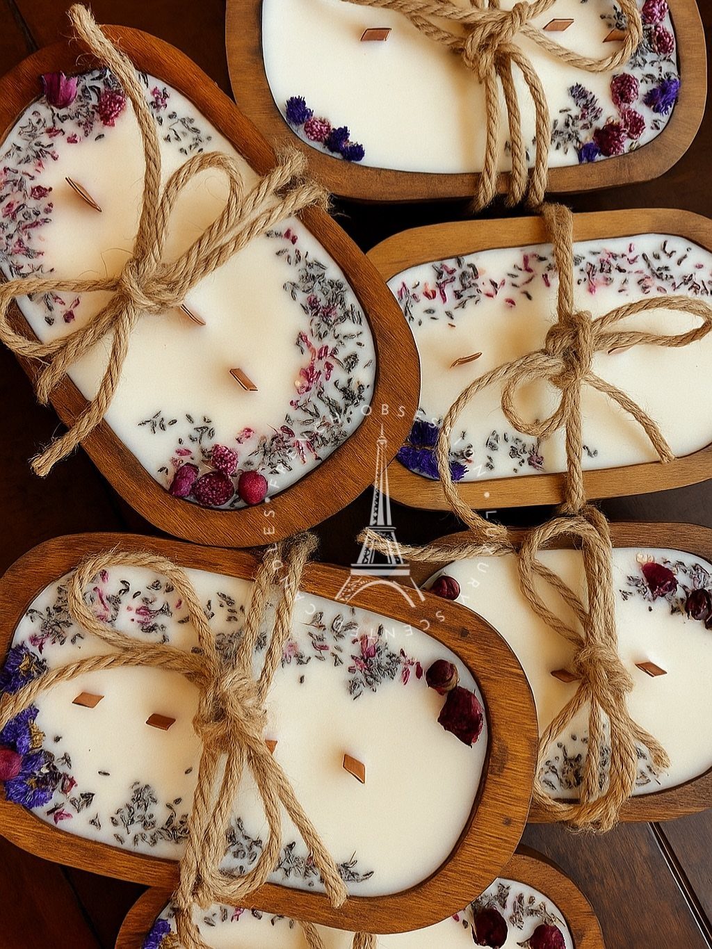 White wax candles in oval wooden bowls decorated with dried flower petals and twine.