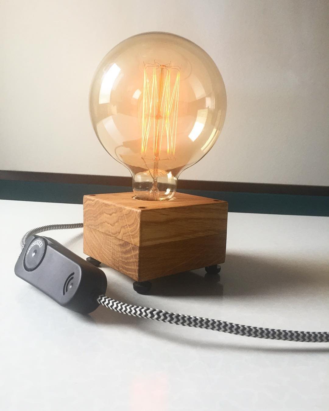 Edison bulb lamp with glowing filaments on a square wooden base