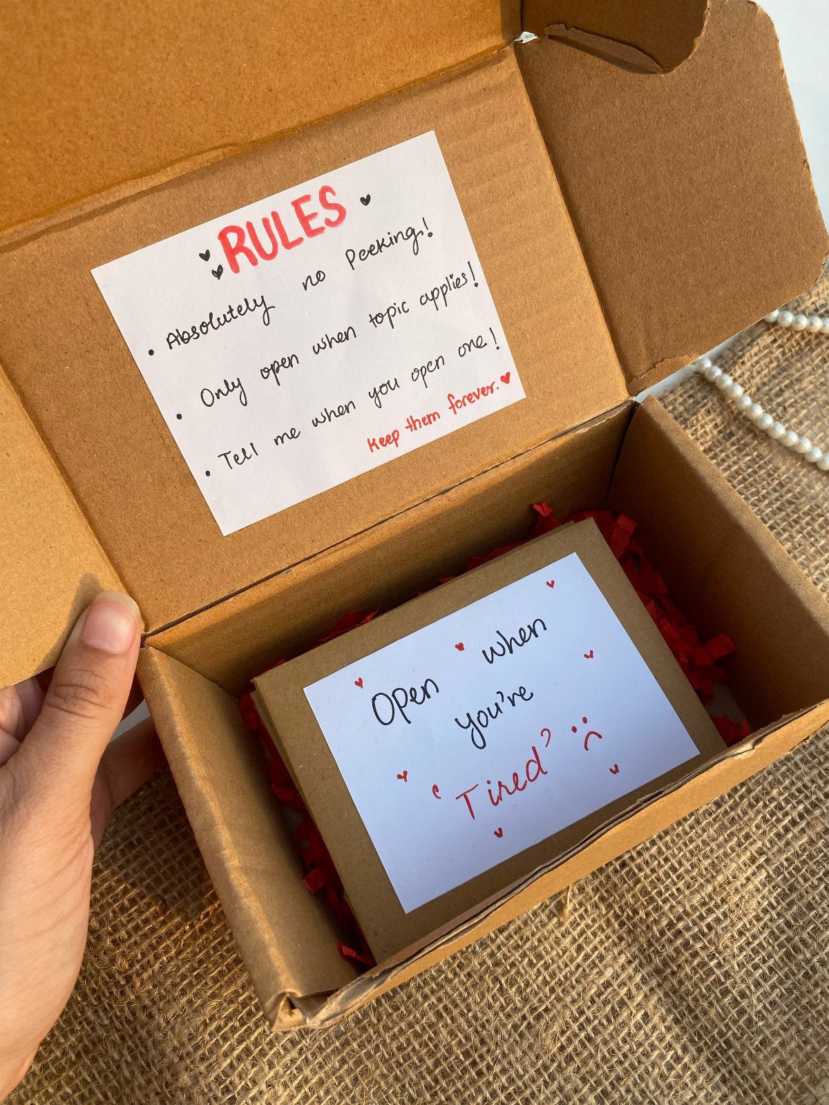 Hand-made open when gift box with red filler and handwritten instruction cards.