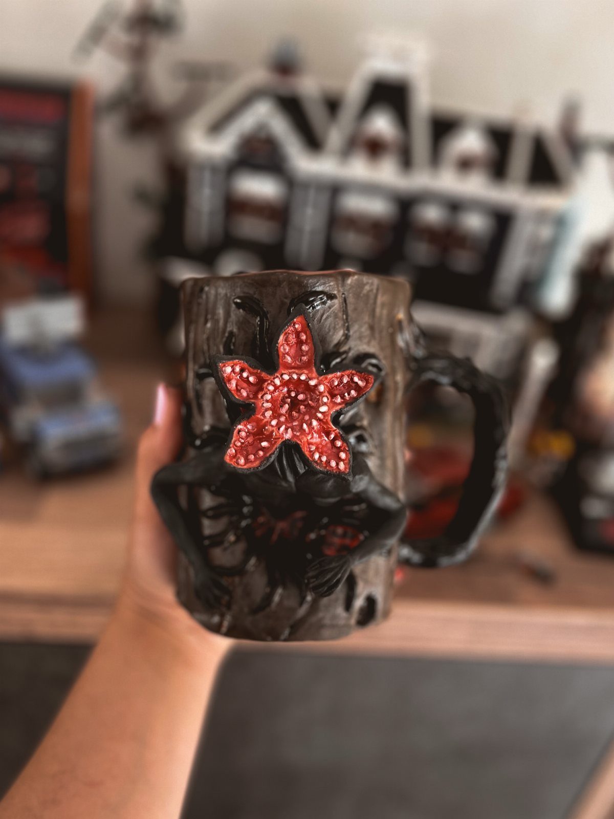 Demogorgon themed ceramic mug with a red glittery star held by a hand.