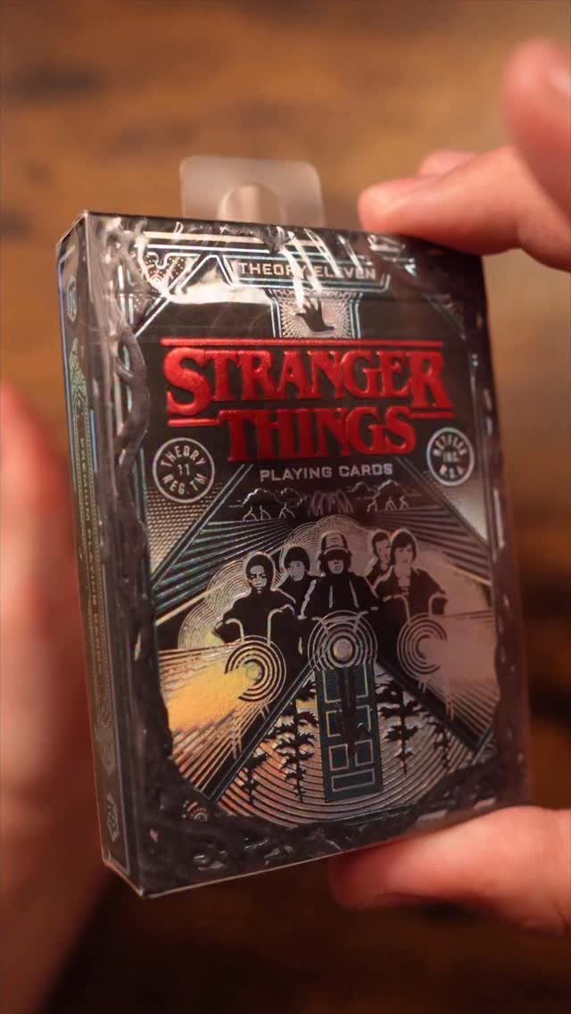 Stranger Things playing cards in plastic packaging held by two hands.