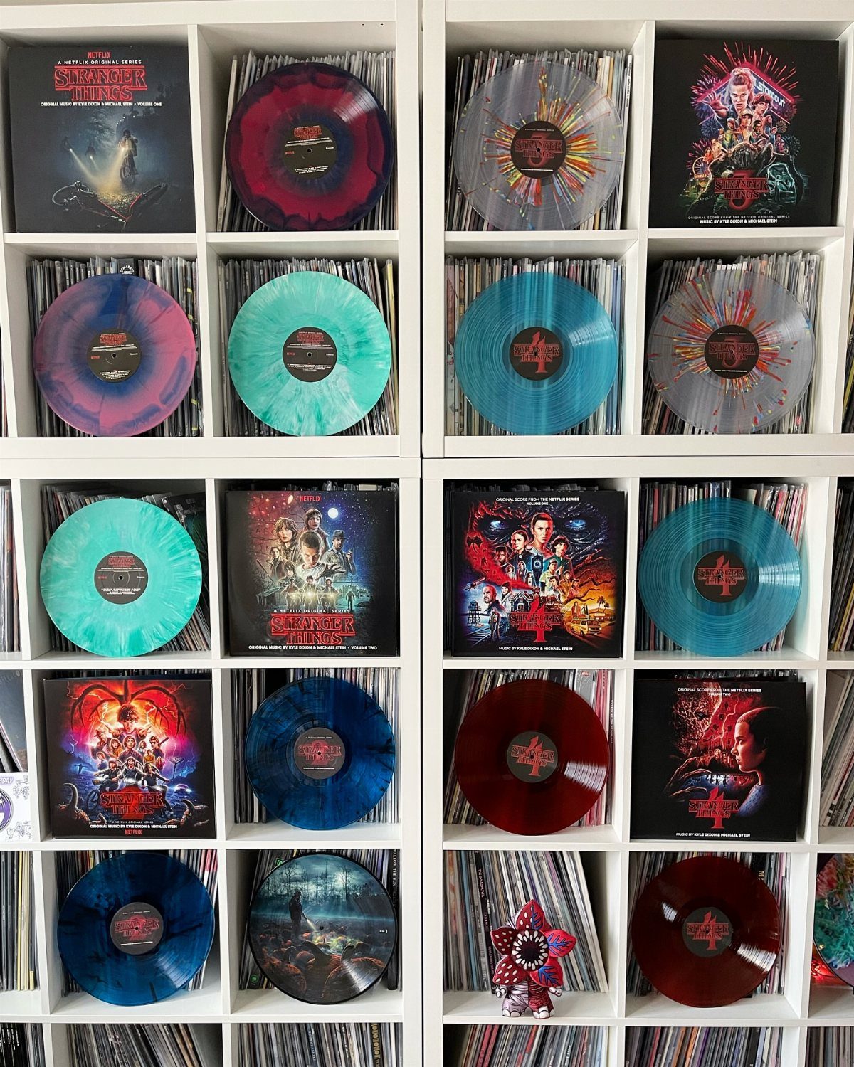 Stranger Things vinyl records in various colors displayed in a white shelving unit.