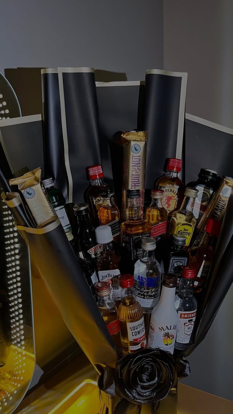 Bouquet of miniature liquor bottles wrapped in black and gold decorative paper.