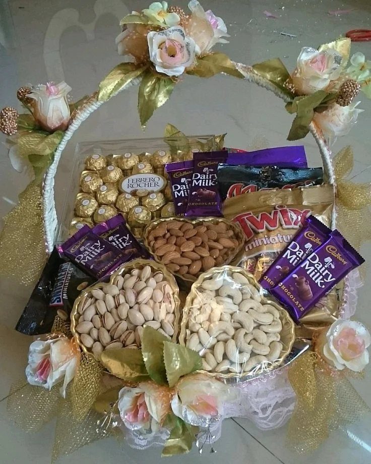 Gift basket filled with chocolates and nuts, decorated with peach roses and gold leaves.