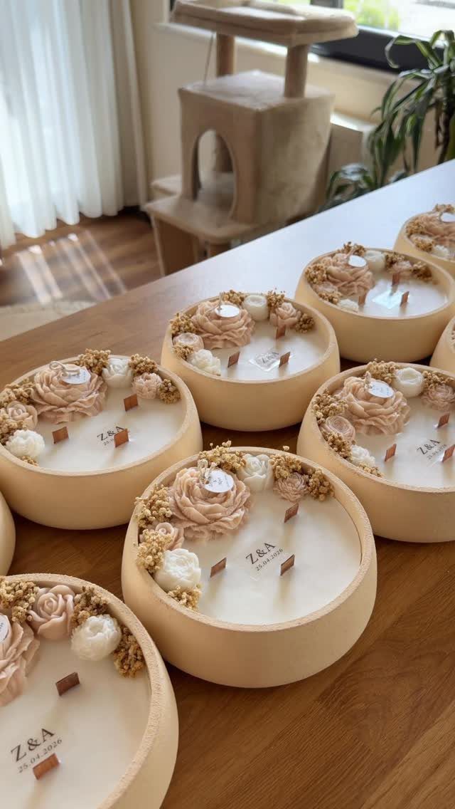 Cream-colored round candles decorated with frosting swirls and dried flowers on a table