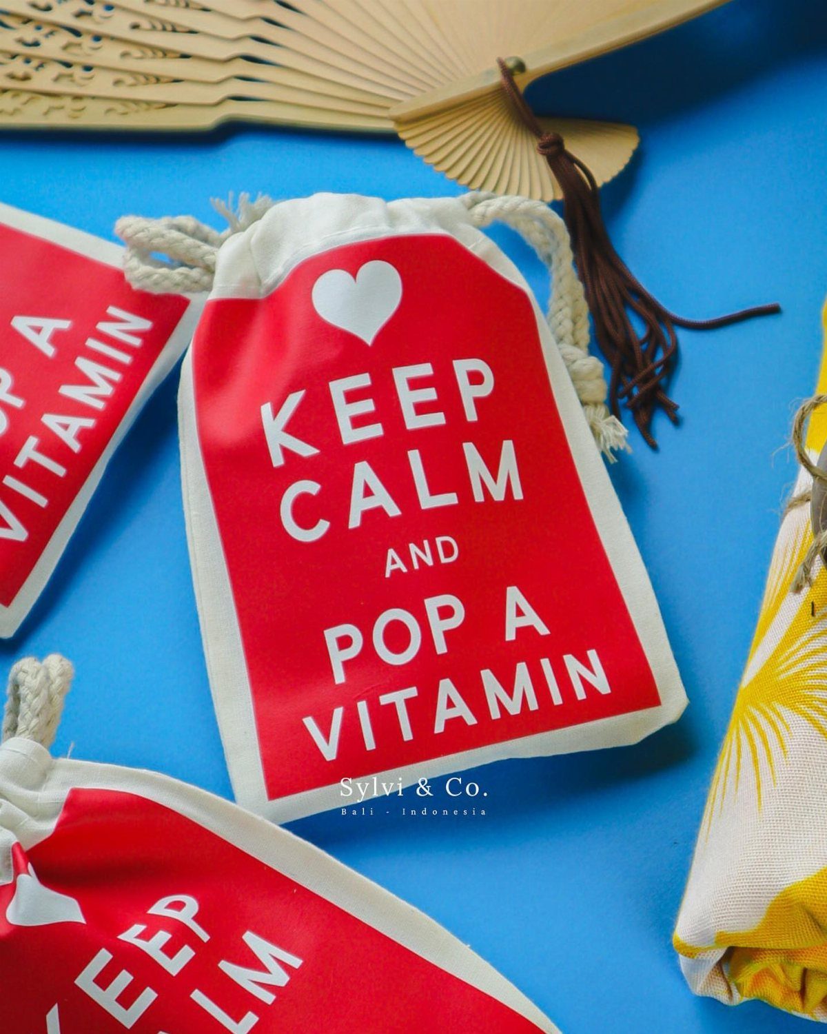 White drawstring pouches with red labels saying Keep Calm and Pop a Vitamin.