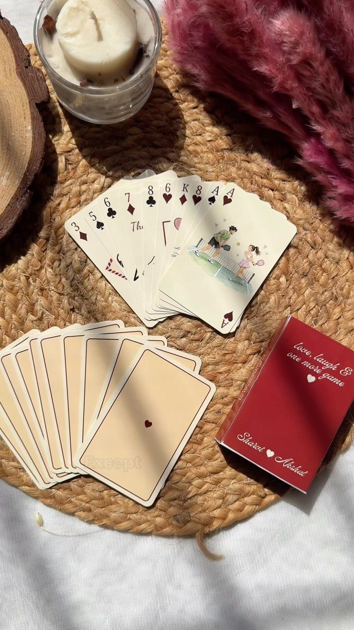 Custom playing cards and a red box on a woven straw mat.