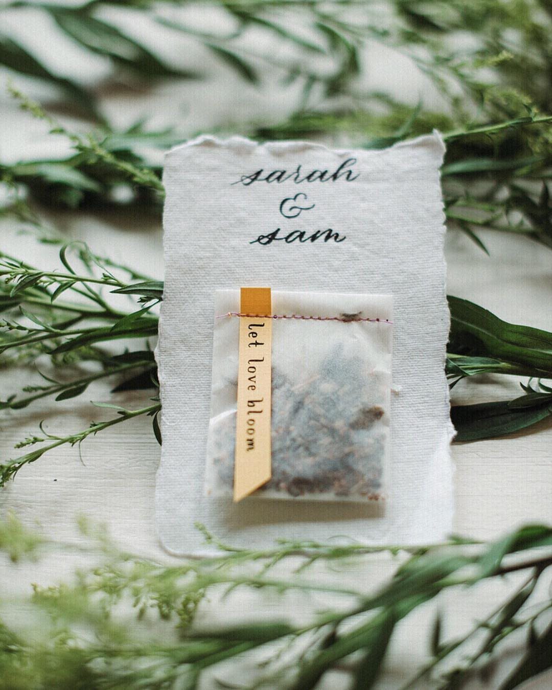 Seed packet attached to a personalized wedding card surrounded by green leaves