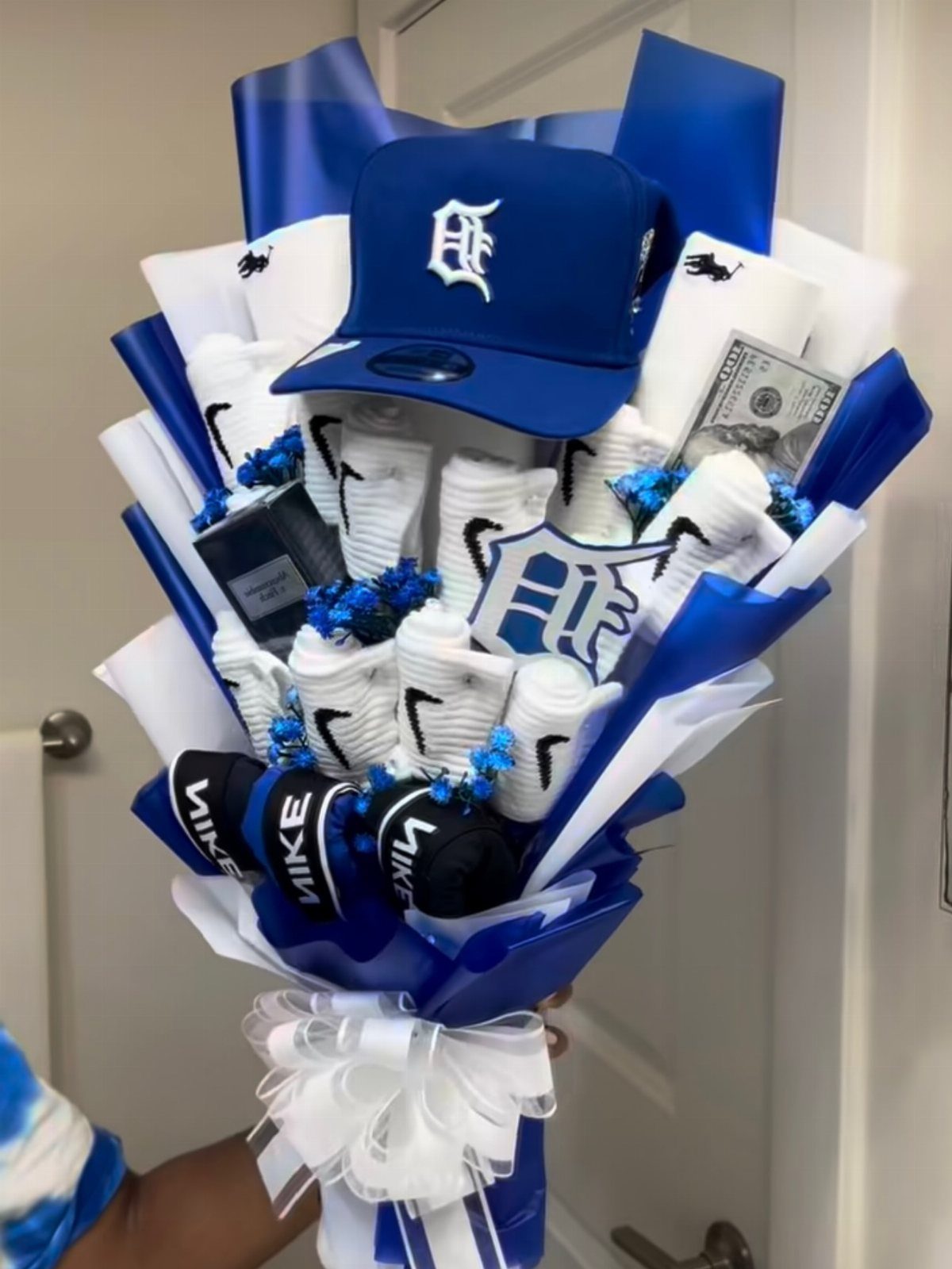 Gift bouquet with blue baseball cap, Nike socks, and cash in blue wrapping.